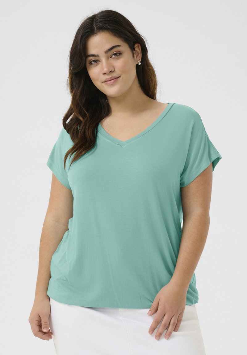 Mint green short-sleeve top with a v-neck design, soft texture, and draped fit. The fabric appears lightweight and smooth.