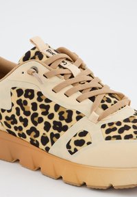 Zapatillas de deporte con estampado de leopardo, con parte superior de ante sintético en beige, cordones en tono marrón y suela de goma texturizada con un patrón en zigzag.