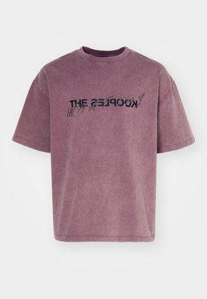 Camiseta de manga corta y corte relajado en un color malva desgastado, con texto negro que presenta un efecto en degradado y un acabado suave y texturizado.