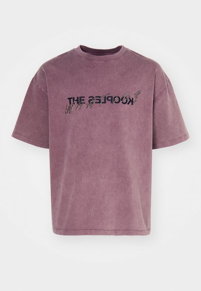 T-maica s kratkimi rokavi, sproščenega kroja v zbledeli mauve barvi, z črnim besedilom v gradientnem efektu in mehkim, teksturiranim zaključkom.