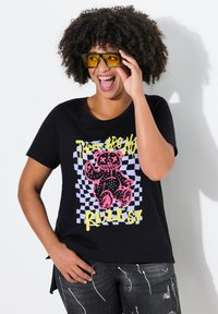 Sort bomulds t-shirt med et grafisk motiv af en pink bjørn på en ternet baggrund og teksten "Der er ingen regler!" i gul.