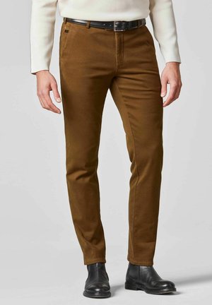 Braune Baumwollchinos mit schmalem Schnitt, versehen mit einer glatten Textur und Taschen vorne, kombiniert mit schwarzen Leder-Ankleboots.