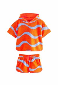 Completo a due pezzi con un top cropped arancione con cappuccio e strisce blu ondulate, abbinato a pantaloni corti arancioni con dettagli blu e vita elasticizzata.