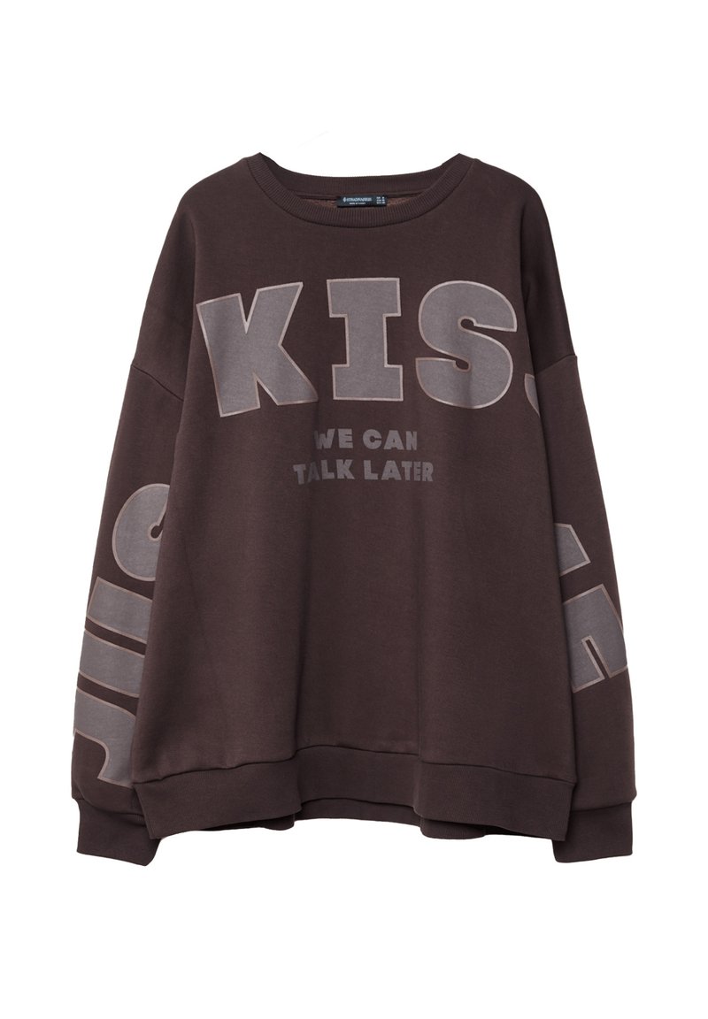 Bruine sweatshirt met een oversized pasvorm, voorzien van grote grijze tekst: "KIS WE CAN TALK LATER" op de voorkant en zijkant. Katoenen stof, ronde halslijn.