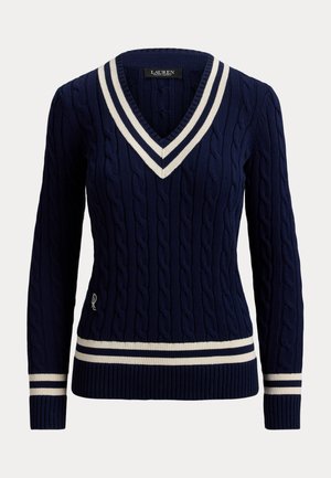 Marineblå kabelstrikket genser med V-hals, hvite doble striper på kragen, ermene og kanten, og en liten brodert logo på nedre side.