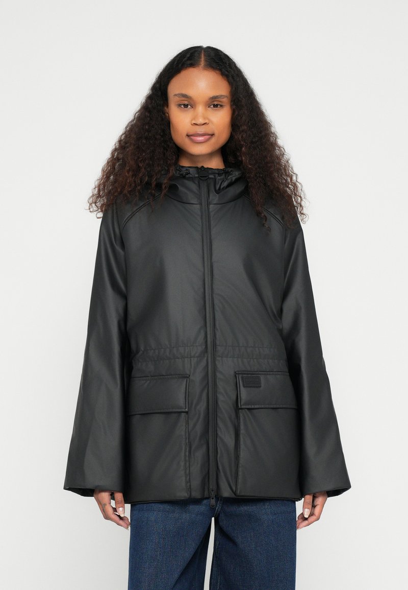 Μαύρο, ελαφρύ μπουφάν με κουκούλα, φερμουάρ μπροστά, δύο μπροστινές τσέπες και φαρδιά μανίκια. Κατασκευασμένο από λείο, αδιάβροχο υλικό.