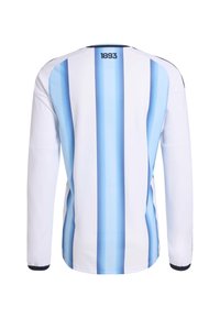 Dugooki nogometni dres s dugim rukavima, bijele boje s dvije vertikalne svijetloplave pruge, teksturirani materijal i crni detalji na manžetama i vratu. Na leđima piše "1893."