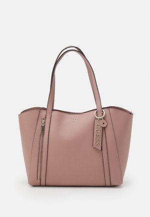 Sac à main mauve Guess avec deux anses, poche zipper verticale à l'avant et étiquette de marque suspendue à une anse sur fond blanc.