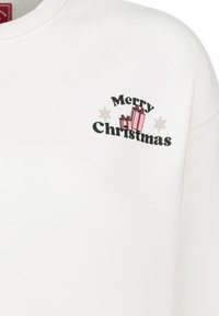 Weißes Sweatshirt mit dem Schriftzug "Frohe Weihnachten" in Schwarz, begleitet von pinken Geschenkillustrationen und Schneeflockenakzenten. Weicher, strukturierter Stoff.