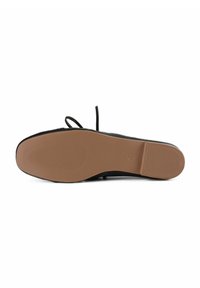Chaussure plate noire avec un dessus lisse, dotée d'une semelle extérieure en caoutchouc durable couleur tan, texturée pour une meilleure adhérence, avec des lacets et des détails de design minimalistes.