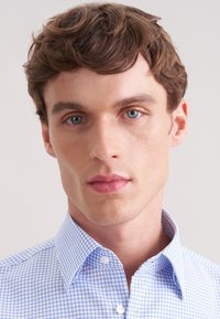 Niebiesko-biała koszula w kratkę z kołnierzem na guziki, z delikatnym wzorem kraty i gładką fakturą, wykonana z lekkiego materiału.