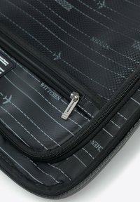 Schwarze Laptoptasche mit strukturiertem Äußeren, weißen Nahtlinien und einem Reißverschluss mit einem Metall-Ziehband. Das Innere ist gemustert.