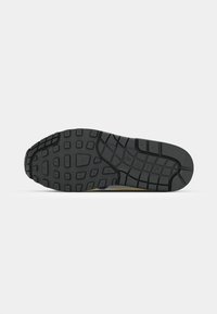 Black rubber sole with a textured pattern, featuring square and rectangular treads for grip. Notable yellow accent along the edge.