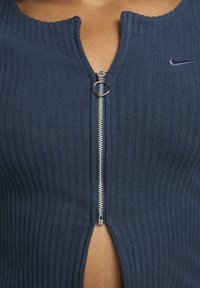 Navy gerippter Oberteil mit einem Reißverschluss vorne, mit einem gewellten Ausschnitt und einem kleinen Nike-Logo. Hergestellt aus einem strukturierten Stoff, slim fit Design.