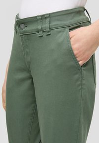 Groene katoenen broek met knoopsluiting en zijzakken, voorzien van gestikte details en een gladde textuur. De tailleband heeft verstelbare banden.