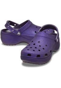 Lila Clogs aus leichtem Material, mit glänzender Oberfläche, offenen Löchern zur Belüftung und einer strukturierten Oberfläche für einen besseren Halt.
