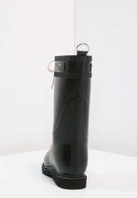 Stivale da pioggia in gomma nera con una texture liscia, design robusto, linguetta sul retro per una facile calzata e un dettaglio di lacci bianchi a contrasto.