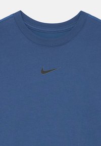 Camiseta de algodón azul con cuello redondo, que presenta un logo negro de Nike en el frente. La tela tiene una textura suave y un color sólido.