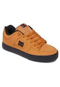 Hnedé kožené skate topánky majú čiernu gumovú podrážku, čierne akcenty, okrúhlu špičku a výrazné logo DC na boku a jazyku.