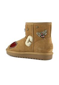 Kozorohavé kožené kotníkové boty v barvě tan se vyznačují vyšívanými detaily, včetně červeného srdce, včely a písmene "C". Doplňují je hvězdicovité cvočky a texturovaná podrážka.
