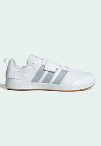 Chaussure de sport blanche avec des rayures grises, fermeture à lacets à l'avant, bride en Velcro, semelle texturée et inscription "0 degré de drop" sur le côté du talon.