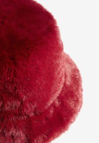 Punane vale karvane aksessuaar, millel on pehme ja pehme tekstuur ning ümar kuju. Pind on läikiv ja selle paksus varieerub.