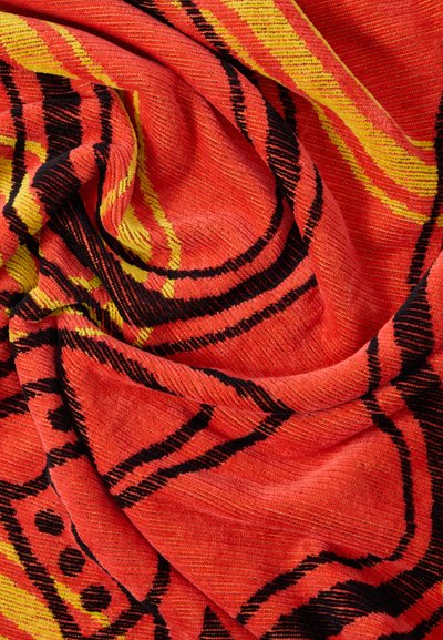 Απαλό ύφασμα με αφηρημένα γεωμετρικά σχέδια σε κόκκινο, κίτρινο και μαύρο, εμφανιζόμενο με ρυτίδες και πτυχώσεις.