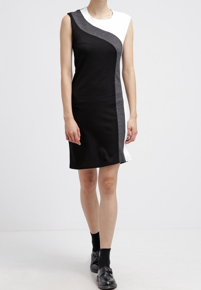 Czarna i szara sukienka bez rękawów z białym akcentem, o asymetrycznym kroju i gładkiej fakturze tkaniny. Długość do połowy uda.