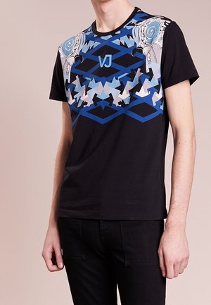 T-shirt noir à manches courtes présentant un motif géométrique bleu et blanc sur les épaules et un logo central "VJ" en bleu.