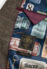 Bruin geruit stoffen jack met een blauw dessinvoering waarin vintage kaartontwerpen zijn weergegeven. Voorzien van een label met "next" en een label met "skinny fit".