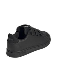 Zapatilla negra de Adidas con tres correas de Velcro, paneles laterales perforados, suela texturizada y collar acolchado, mostrada desde un ángulo lateral trasero.