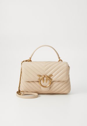 Sac à main matelassé beige avec un détail en métal circulaire doré représentant deux oiseaux. Il comprend une bandoulière en chaîne amovible et une texture lisse.