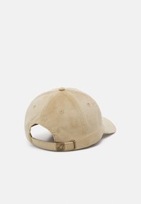 Beige corduroy cap with a curved brim, adjustable strap at the back, and a metal logo tag. Textured fabric with stitching details.