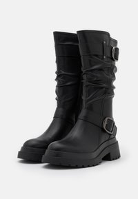 Para czarnych skórzanych kozaczków do połowy łydki z grubymi podeszwami, zamkiem bocznym, marszczonymi detalami i dwoma srebrnymi klamrami.