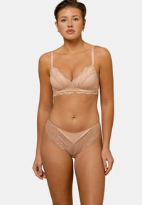 Ensemble de lingerie nude avec dentelle comprenant un bralette à bretelles ajustables et un string assorti, présentant une texture lisse et un design délicat.