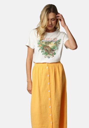 T-shirt blanc avec un motif floral et léopard, associé à une longue jupe jaune texturée avec un bouton sur le devant.