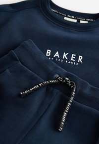 Navy blue sweatshirt and matching sweatpants with "BAKER by Ted Baker" logo on chest and branded drawstring on pants.