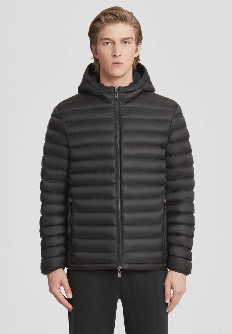 Giacca a vento nera con cappuccio, imbottita, con texture a rombi orizzontali, chiusura con zip frontale e tasche laterali. Tessuto liscio e lucido; design minimale.
