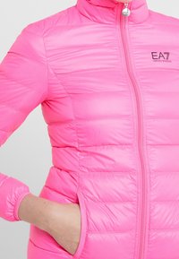 Rosa puffjacka med horisontell quiltad vaddering, ståkrage, hel dragkedja, två sidofickor och EA7-logotyp på bröstet.