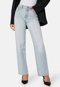 Lichtblauwe high-waisted jeans met een rechte pijp, vijfzakken ontwerp en vervaagde textuur. Gecombineerd met zwarte puntige hakken.