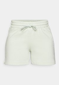 Světlé zelené teplákové šortky s elastickým pasem, šňůrkou, bočními průstřihy a jemným logem na levé noze. Měkká, strukturovaná látka.