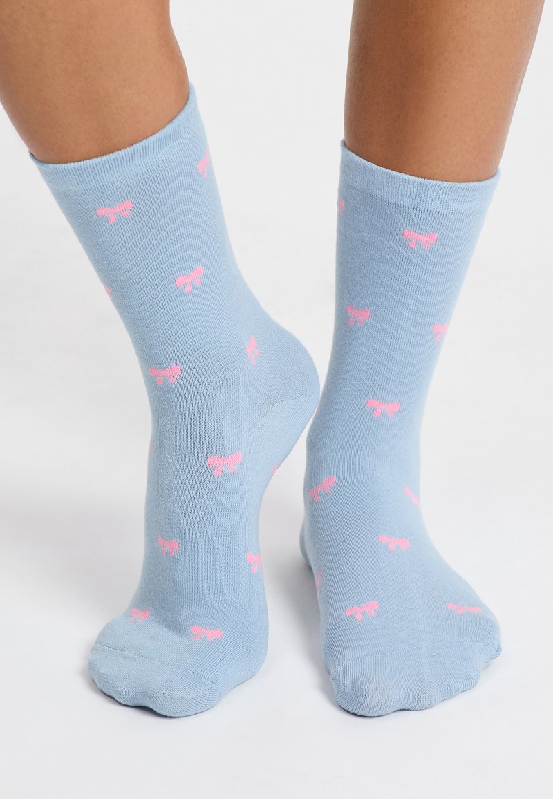 Calcetines de algodón azul claro con patrones de lazo rosa, de longitud media hasta la pantorrilla, textura suave y punteras y talones reforzados.