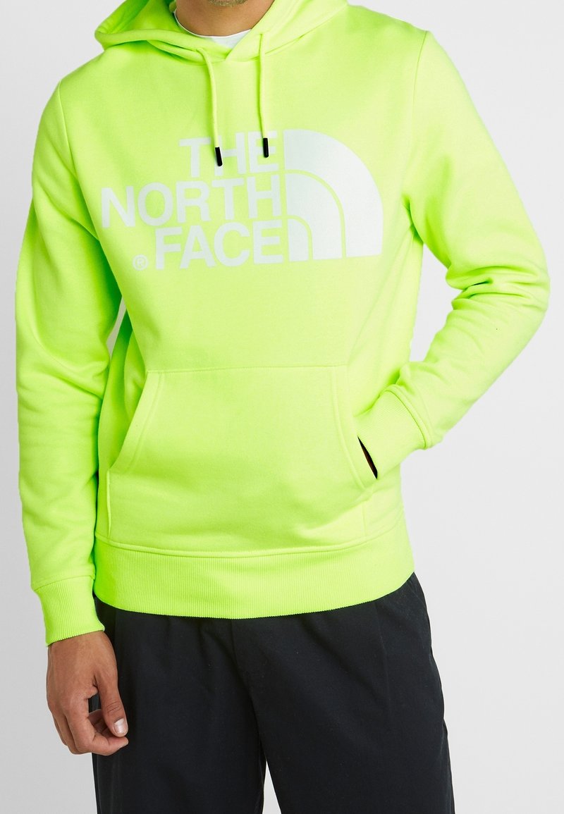 Ljus neongrön hoodie gjord av mjukt tyg, med en stor vit logotyp, justerbar dragsko på huvan och framficka.