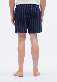 Σκούρο μπλε σορτς με κατακόρυφες λευκές ρίγες, με ελαστική μέση και άνετη εφαρμογή. Υφασμένο βαμβακερό ύφασμα με υφή.