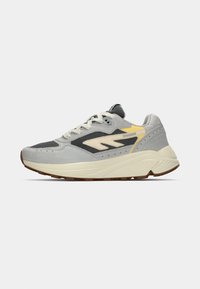 Grey sneaker featuring a mix of suede and mesh materials, a thick white midsole, yellow accents, and a textured brown outsole.