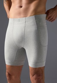 Boxers pour hommes gris clair en tissu doux et extensible avec des coutures plates et une coupe ajustée, dotés d'une taille sans logo.