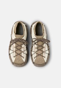 Kengät, joissa on teksturoitu kumipohja, vaalean kerma ja ruskea verkkopinta sekä ruskeat nauhat. Pohjassa huomattavaa vaaleaa pilkuttamista.