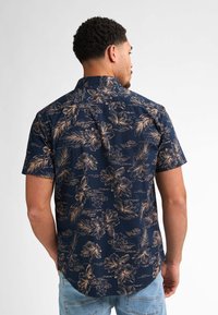 Camicia cortas maniche blu navy con un motivo floreale dorato, colletto con bottoni e orlo curvo, realizzata in tessuto leggero.
