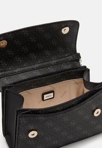 Černá kožená kabelka přes rameno s texturovaným povrchem, zlatými detaily a béžovým interiérem. Obsahuje logo a několik přihrádek.