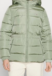 Olivově zelená péřová bunda, lesklý nylonový materiál, prošívaný design, přední zip, nastavitelná kapuce, elastické manžety, boční kapsy.